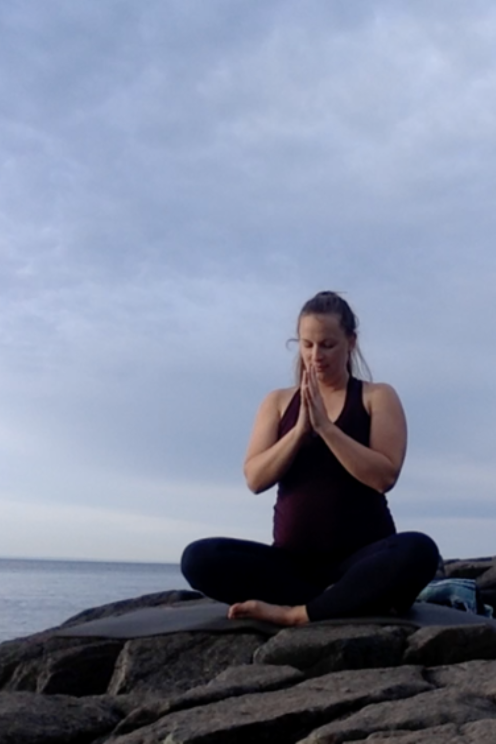 A person meditating on a wooden deck overlooking the peaceful waters of Lake Superior, surrounded by the soothing colors of dusk.